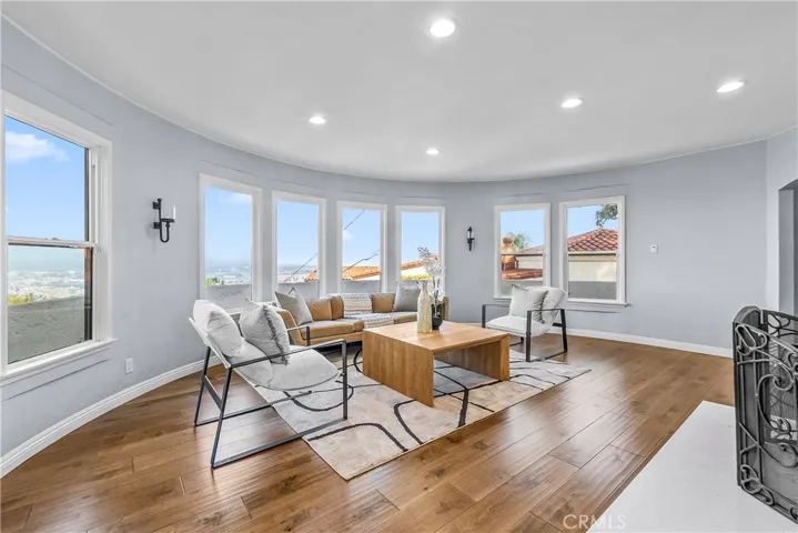 The living room is appointed with rich hardwood floors, an elegant stone fireplace, and subtle designer tones.