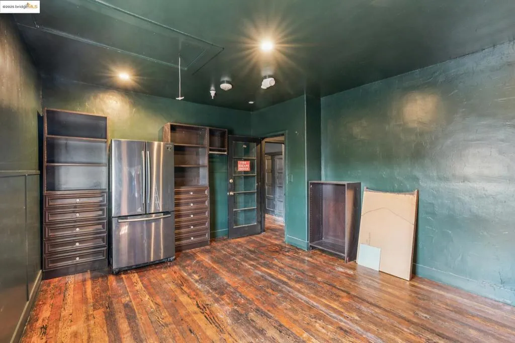 Kitchen featuring freestanding refrigerator, dark wood-type flooring, open shelves, and a textured wall