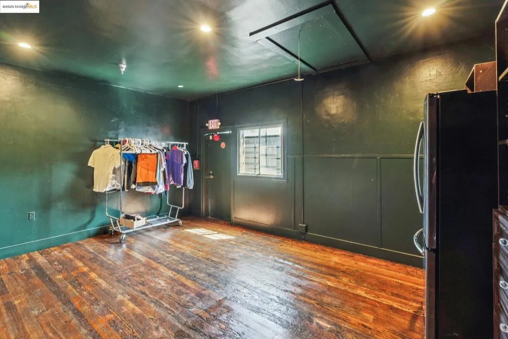 Unfurnished room featuring dark wood-style flooring and attic access