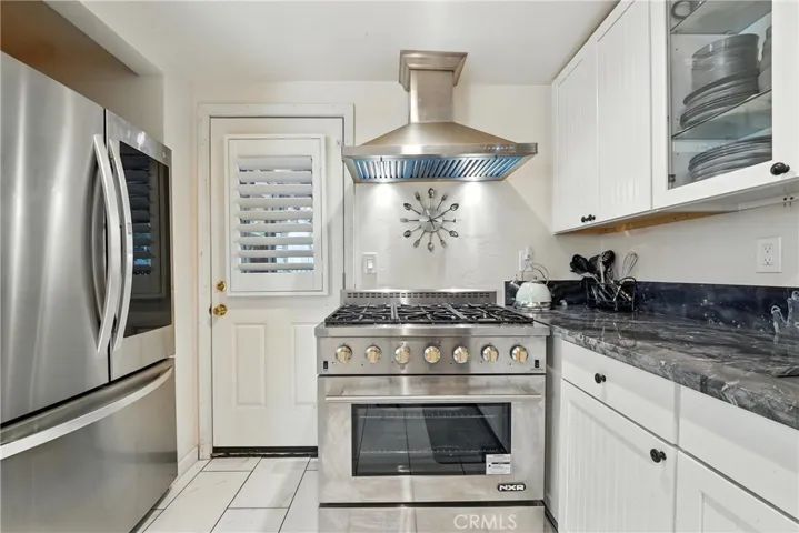 Main home kitchen facing east showing granite countertop, 6-burner stove and stainless steel refrigerator