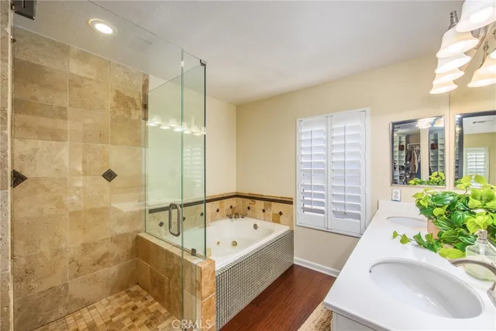 Primary ensuite with tiled and frameless shower, jacuzzi tub