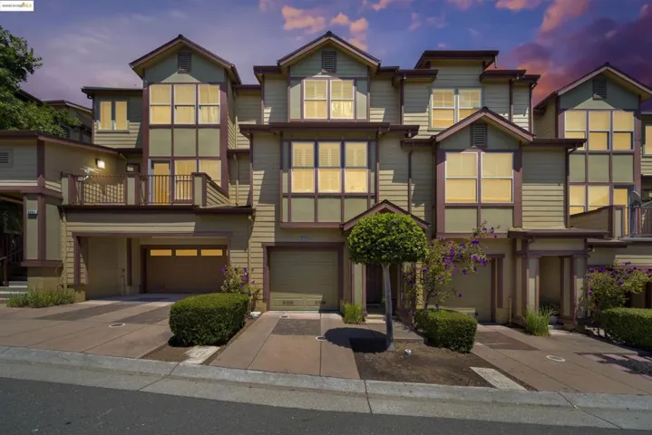 View of front of property featuring a balcony, driveway, and a garage