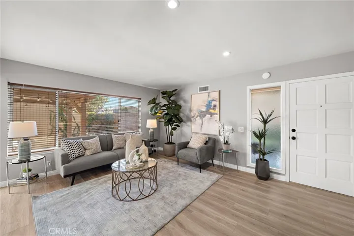 Entry Door with Large Sidelight Window Opens to the Gorgeous Living Room with Wood Vinyl Flooring and Recessed Lighting