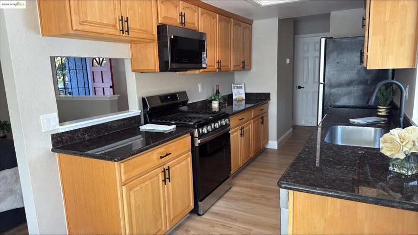 Kitchen featuring appliances with stainless steel finishes, dark stone countertops, and light wood-style floors