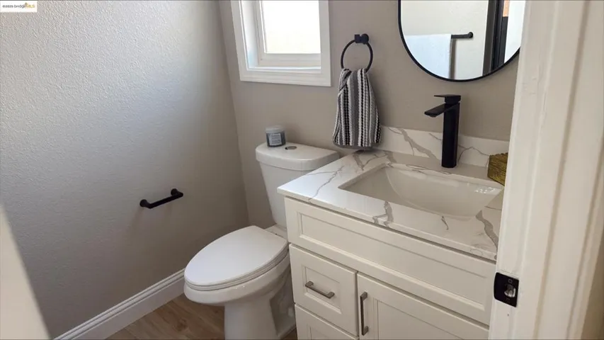 Bathroom featuring a textured wall, vanity, and wood finished floors