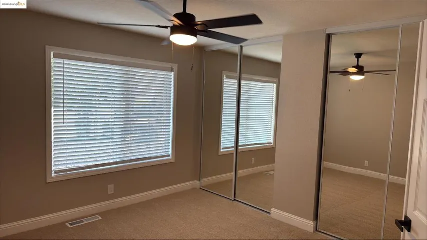 Unfurnished bedroom featuring light carpet and ceiling fan