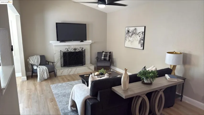 Living room with light wood finished floors, a premium fireplace, and ceiling fan