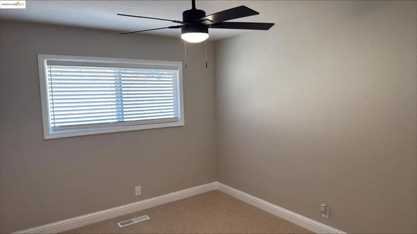Empty room featuring light carpet and ceiling fan
