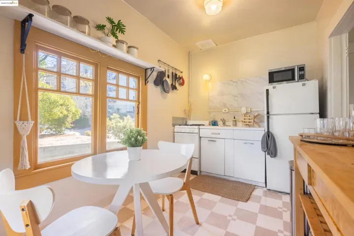 Kitchen featuring white appliances, healthy amount of natural light, white cabinetry, and light countertops
