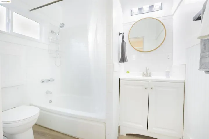 Bathroom with shower / bath combo with shower curtain, vanity, and light wood-style floors