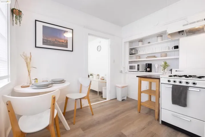 Kitchen with white appliances, open shelves, light wood-style flooring, white cabinetry, and under cabinet range hood