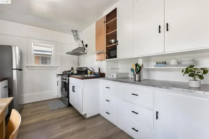 Kitchen featuring white cabinets, stainless steel appliances, dark wood-style floors, open shelves, and decorative backsplash