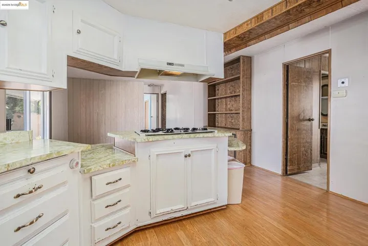 Kitchen with white cabinetry, light wood finished floors, under cabinet range hood, and white gas stovetop