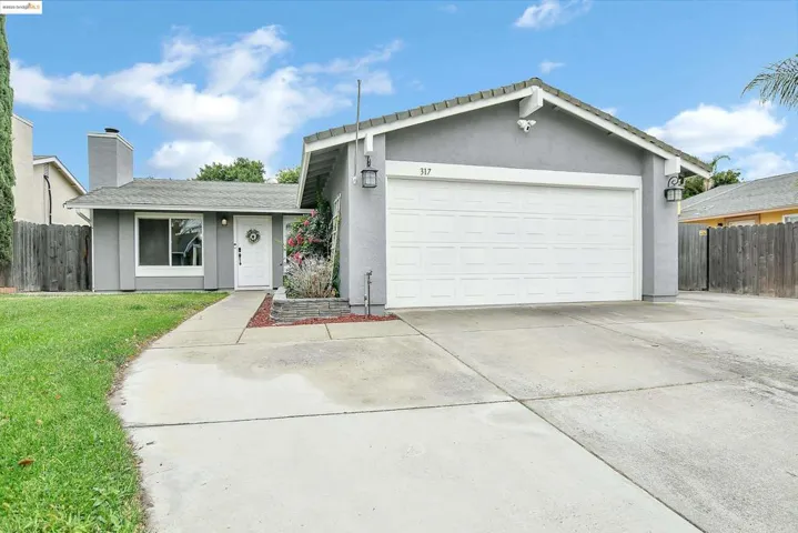 Single story home featuring stucco siding, driveway, a chimney, and an attached garage