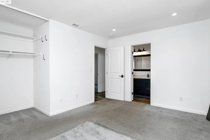 Unfurnished bedroom with carpet flooring, ensuite bath, and recessed lighting