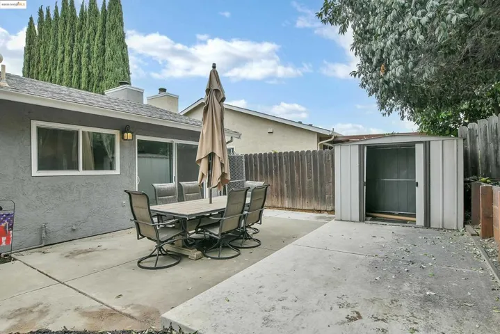Fenced backyard with a storage shed, a patio, and outdoor dining area