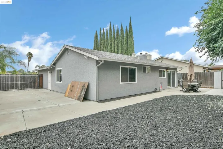 Back of property with stucco siding, a patio area, roof with shingles, and a chimney