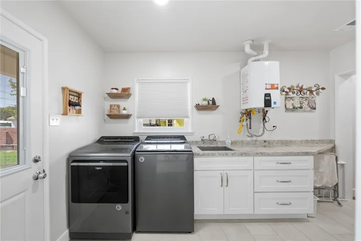 Indoor laundry with tankless water heater, sink and counter top great for folding clothes