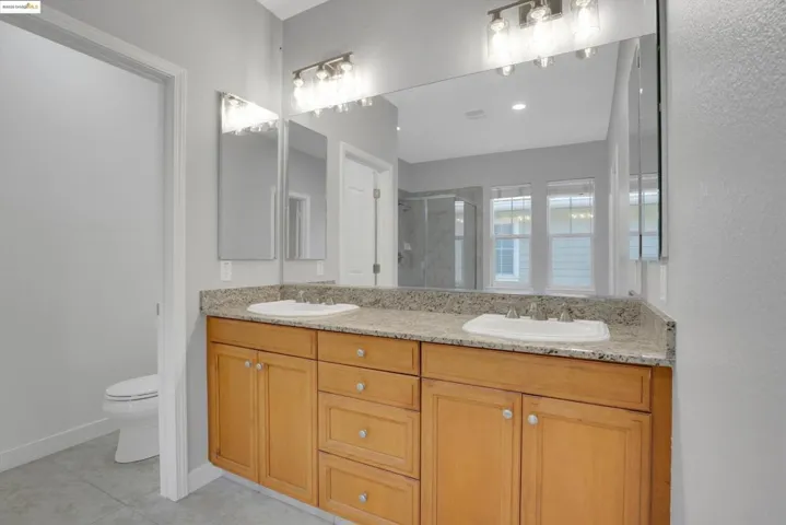 Bathroom featuring a shower stall, double vanity, and light tile patterned flooring