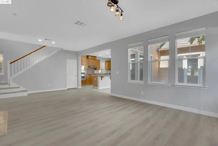 Unfurnished living room with light wood-style flooring, recessed lighting, and stairway