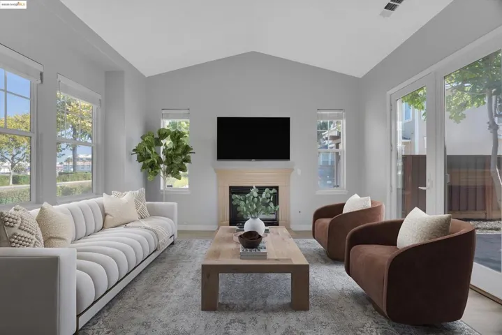 Living room with a glass covered fireplace, lofted ceiling, and wood finished floors