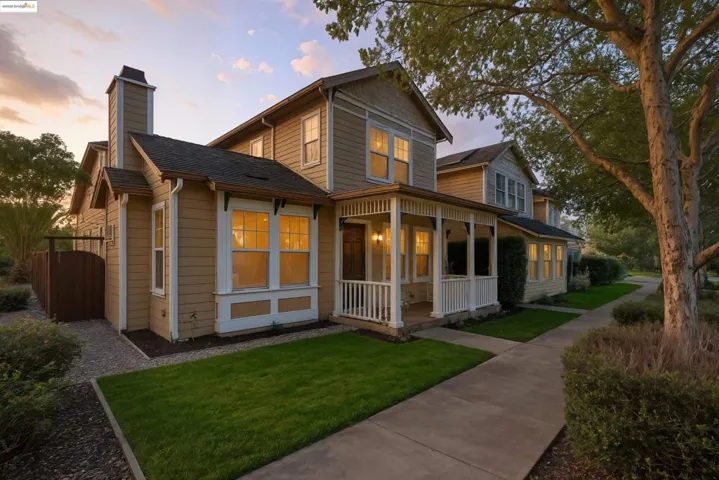 Back of property at dusk featuring covered porch, a yard, a chimney, and roof with shingles