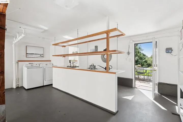 Kitchen with open shelves, concrete flooring, and independent washer and dryer