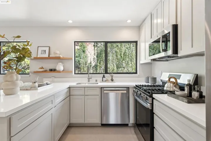 Kitchen with appliances with stainless steel finishes, open shelves, plenty of natural light, recessed lighting, and light stone countertops