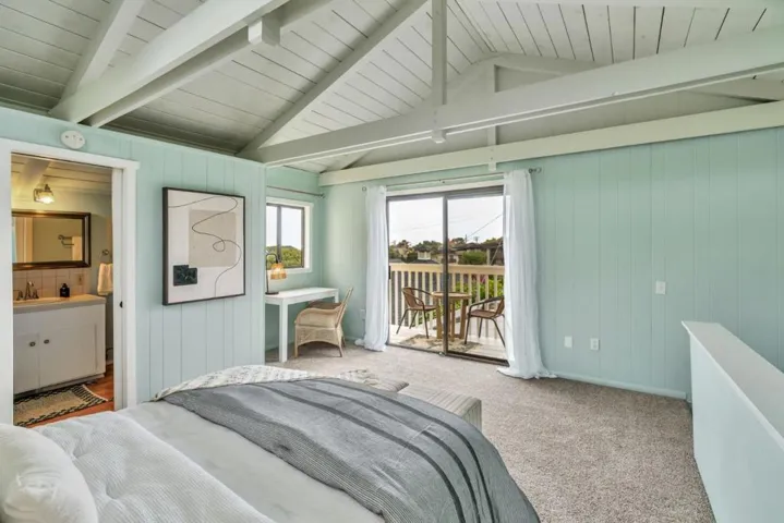 Primary bedroom with vaulted ceilings looking out to balcony and bathroom