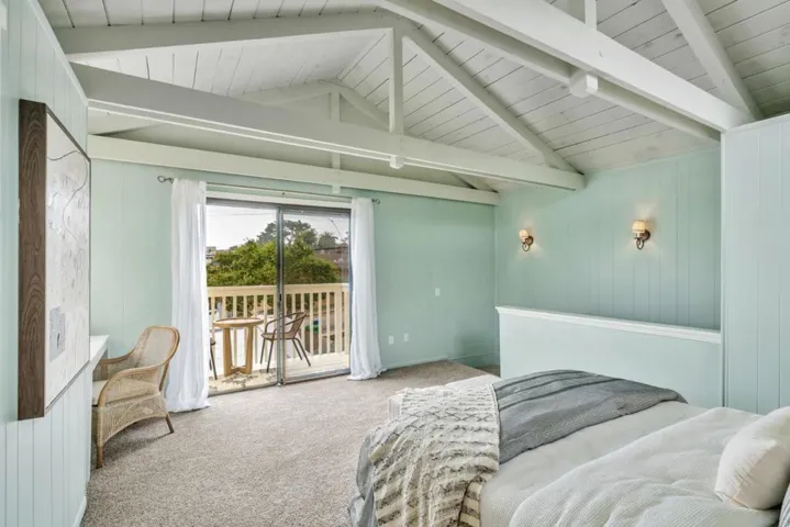Primary bedroom with vaulted ceilings looking out to balcony