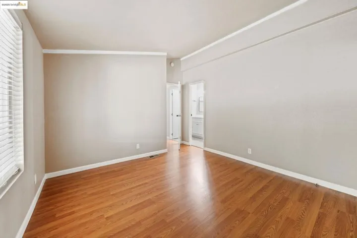 Unfurnished bedroom featuring light wood finished floors, ornamental molding, and ensuite bathroom