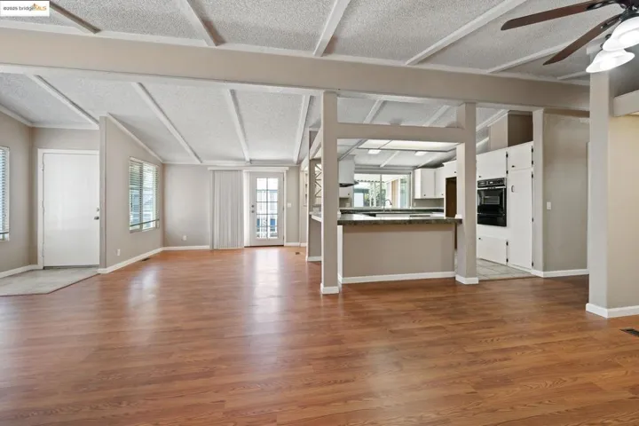 Unfurnished living room featuring ceiling fan, dark wood-type flooring, and a textured ceiling