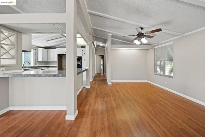 Kitchen featuring healthy amount of natural light, vaulted ceiling, white cabinetry, a peninsula, and a textured ceiling