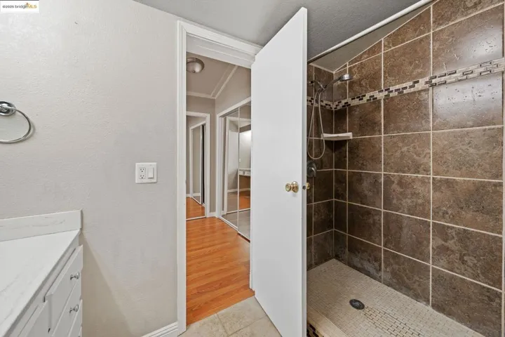 Full bathroom featuring vanity, light tile patterned floors, a stall shower, and vaulted ceiling