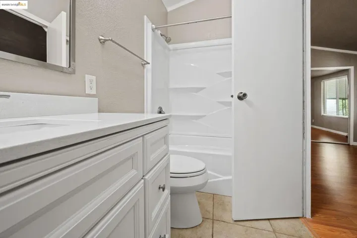 Full bath featuring vanity, light tile patterned floors, a textured wall, shower / washtub combination, and crown molding