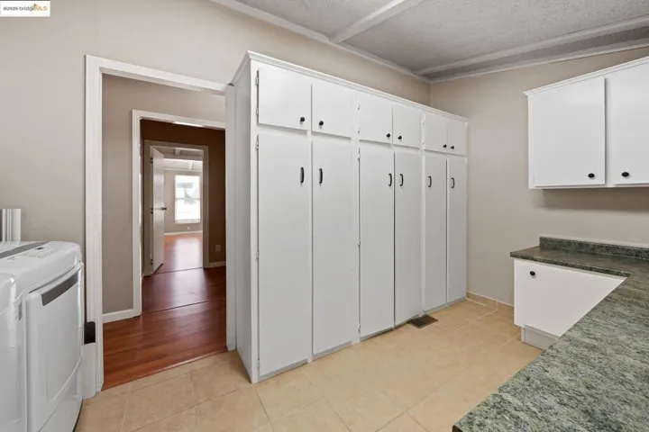 Laundry area featuring light tile patterned flooring, a textured ceiling, and separate washer and dryer