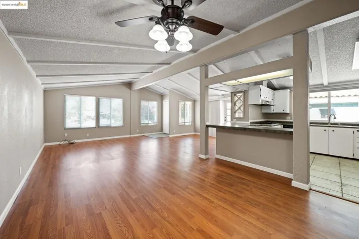 Unfurnished living room with a ceiling fan, dark wood-style flooring, and a textured ceiling