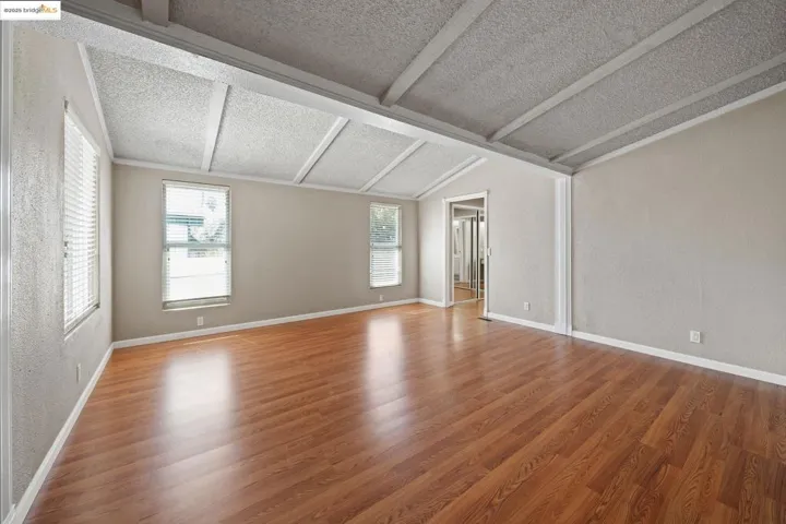 Empty room featuring light wood finished floors, healthy amount of natural light, and a textured ceiling