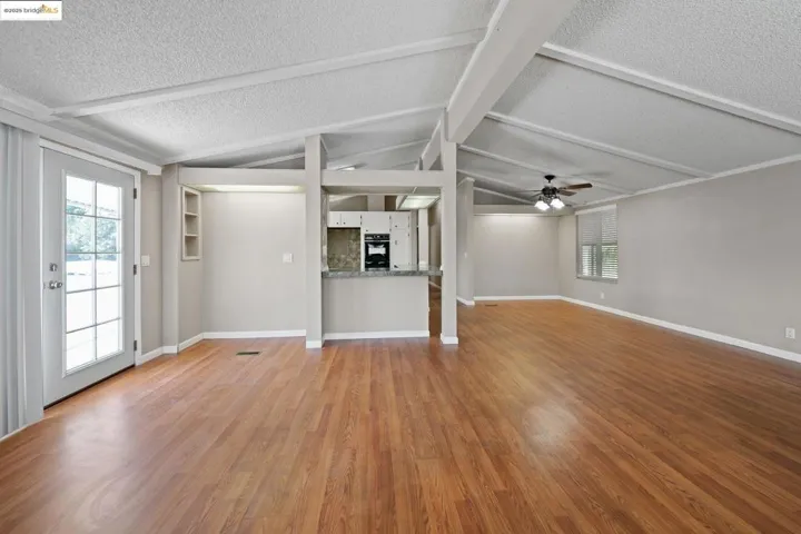 Unfurnished living room featuring plenty of natural light, light wood finished floors, a textured ceiling, and a ceiling fan
