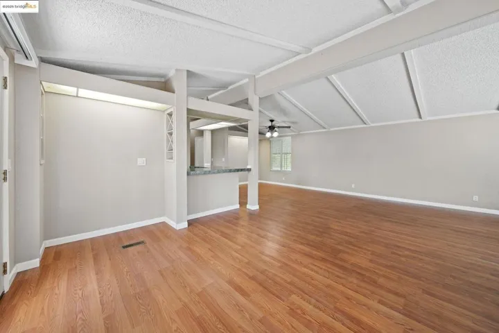 Unfurnished living room featuring ceiling fan, light wood finished floors, and a textured ceiling