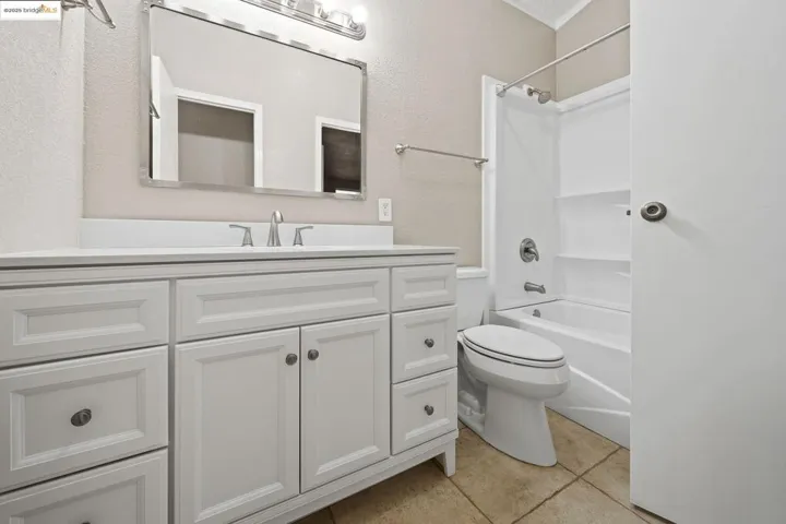 Full bathroom with shower / washtub combination, vanity, light tile patterned floors, and a textured wall