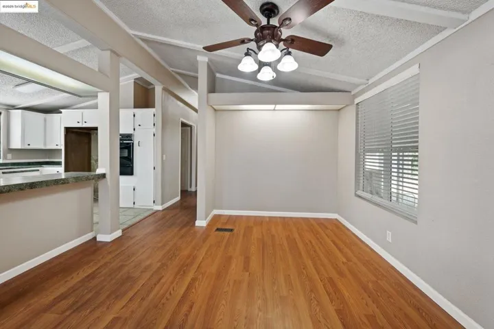 Unfurnished living room featuring lofted ceiling, dark wood-style flooring, a textured ceiling, and a ceiling fan