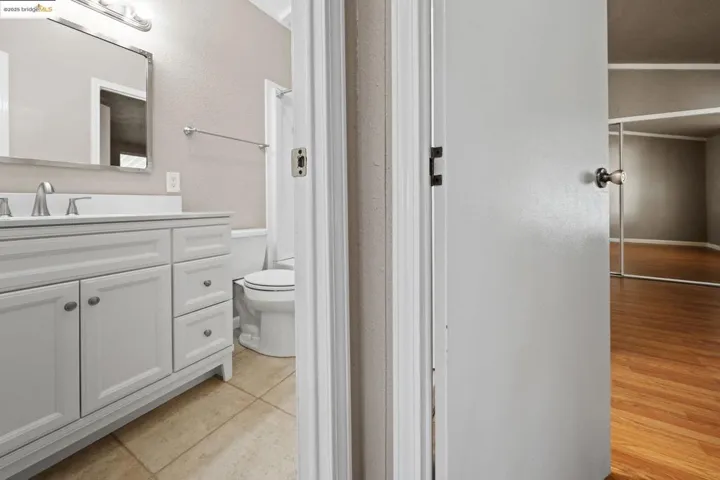 Bathroom with vanity, a textured wall, light tile patterned floors, and a shower