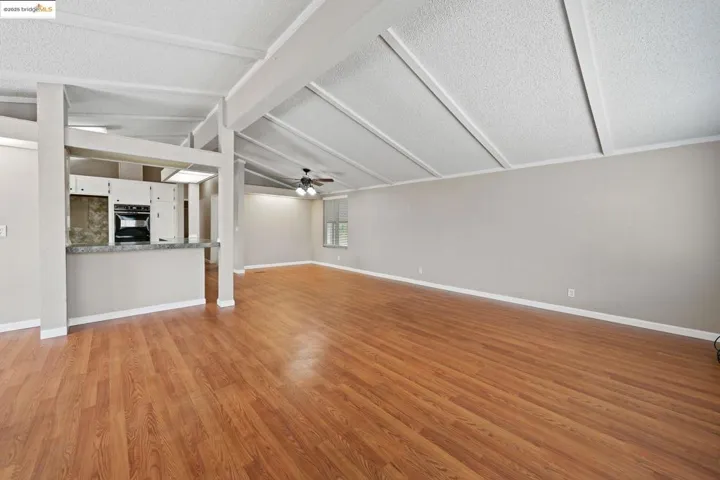 Unfurnished living room with ceiling fan, light wood-type flooring, and a textured ceiling