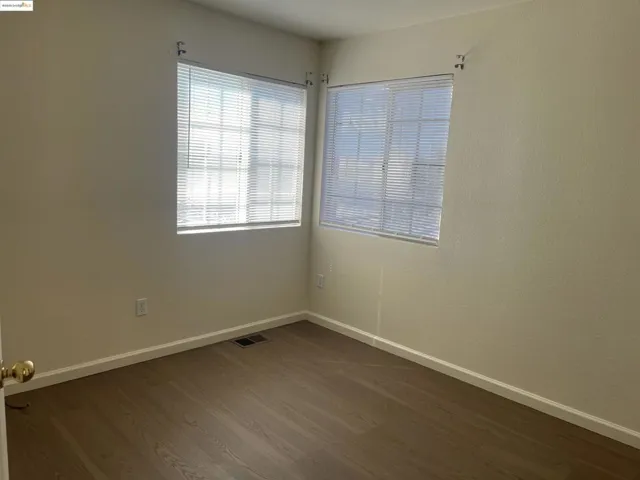 Unfurnished room with baseboards and dark wood-style flooring