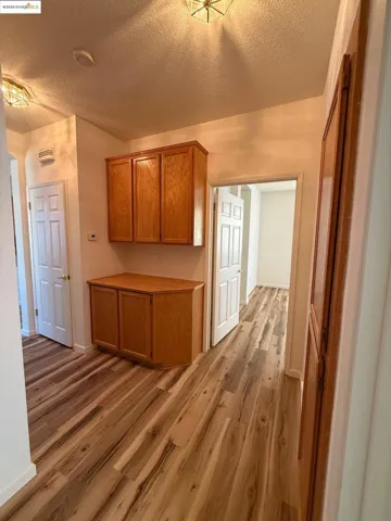 Kitchen featuring a textured ceiling, light wood finished floors, light countertops, and brown cabinets