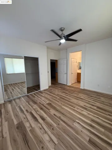 Unfurnished bedroom featuring light wood-style flooring, ceiling fan, a closet, and ensuite bath