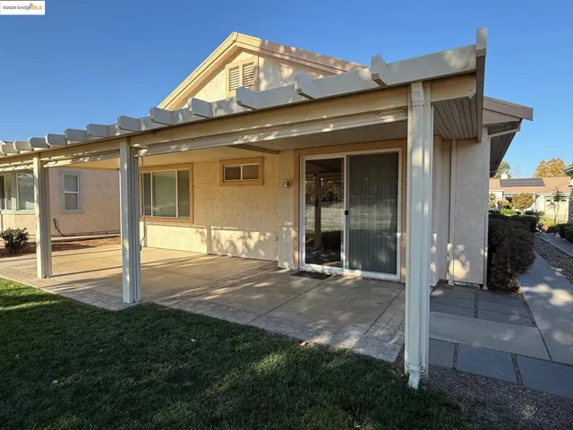 Rear view of house featuring a patio area, a lawn, stucco siding, and a pergola
