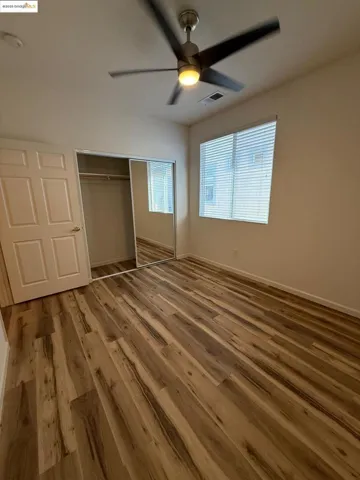 Unfurnished bedroom featuring ceiling fan, a closet, and wood finished floors