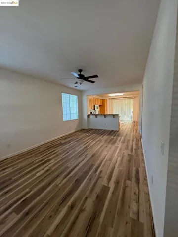 Unfurnished living room with dark wood-style floors and ceiling fan